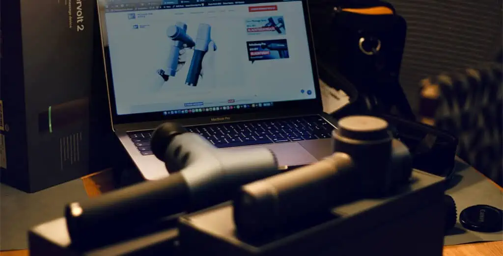 How to Choose a Massage Gun? (What We Learned Testing 70+) 1 Our How to Choose a Massage Gun: Our Laptop on the background showing one of our review comparison of two different massage guns