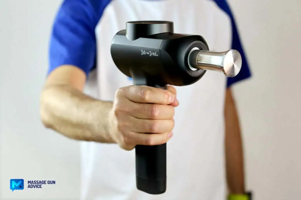 Massage Guns Made in USA - Are There Any at All? 30 Bob And Brad X6 Pro Massage Gun held by a man on a blurry background