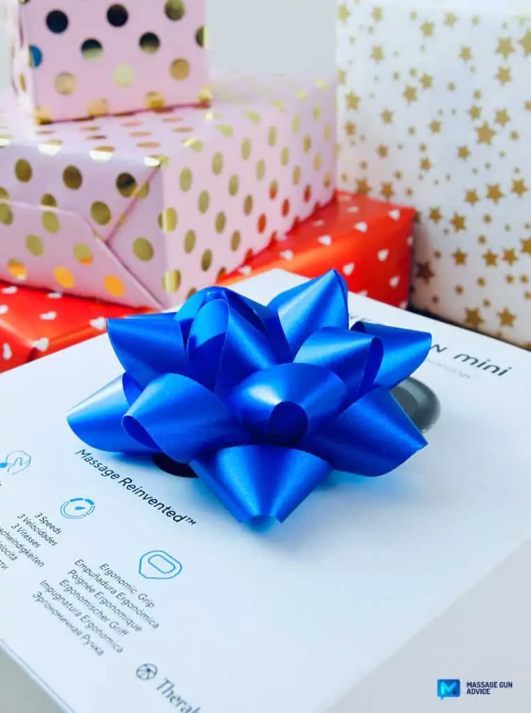 Tech Gifts: Are Massage Guns Good Gift Ideas? - Guide 2026 2 theragun mini in a box with a blue ribbon on top. mini massage un could be the best gift; tech gifts for men.