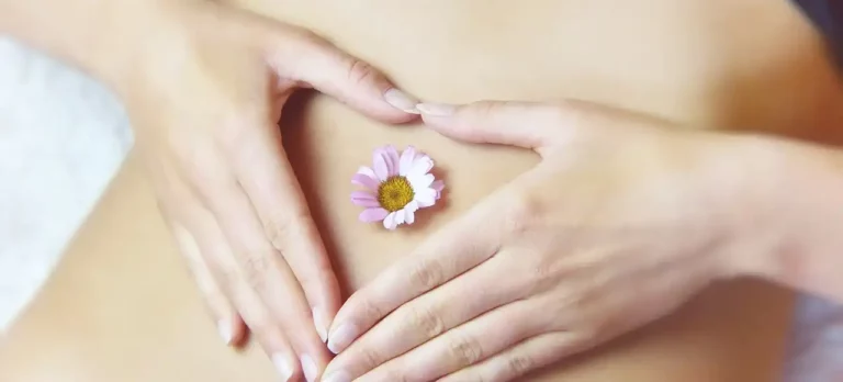 Can You Use a Massage Gun on Stomach? The DOs and DON'ts from our Physical Therapist 10 Woman's Belly with hands heart shape around belly button with flower on top
